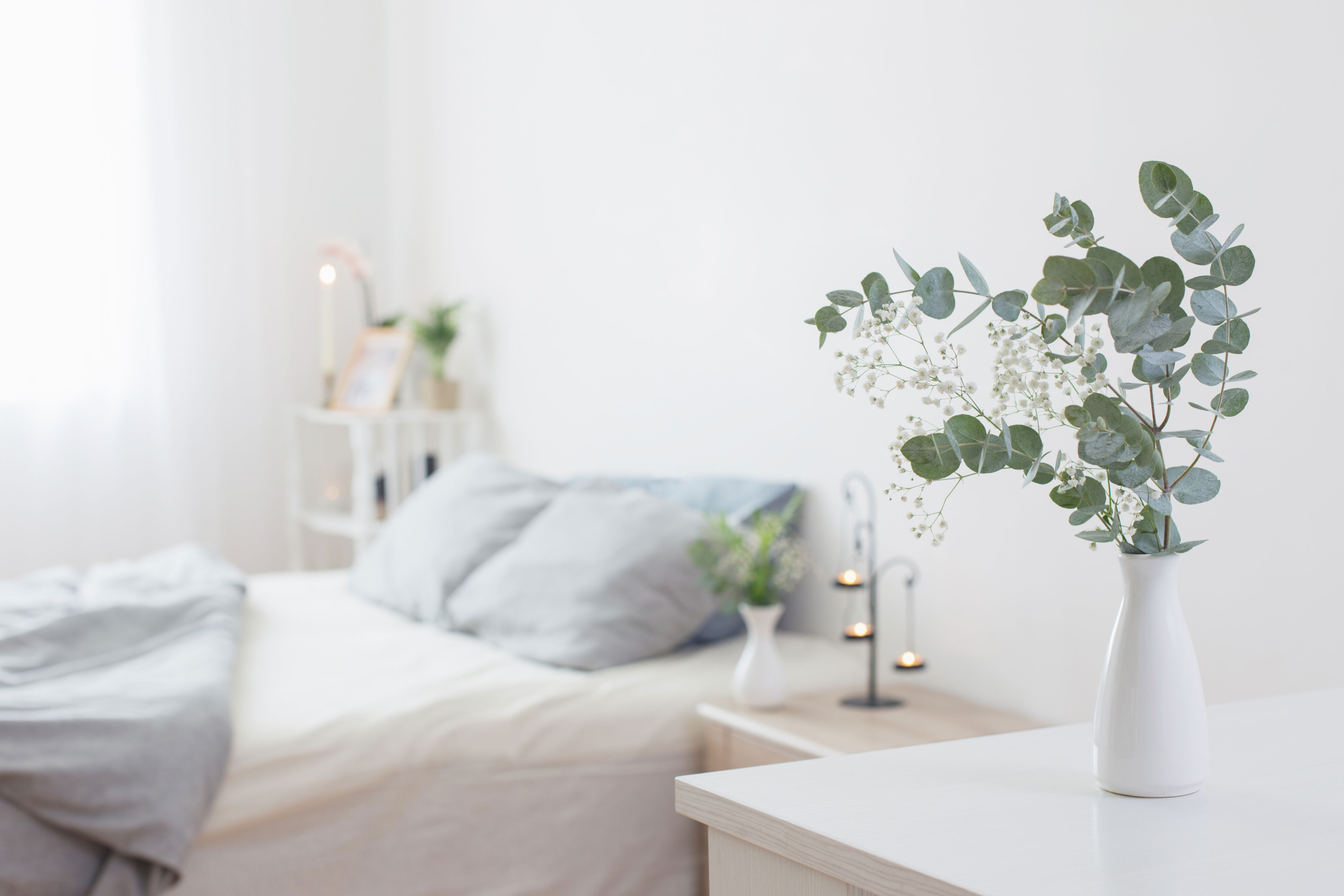eucalyptus-and-gypsophila-in-vase-in-white-bedroom-with-gold-accents-in-background